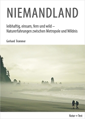 Niemandland: Im Vordergrund sind zwei Wanderer die entlang einer nebelverhangenen Küste auf vereinzelte Berge zulaufenvor einer
